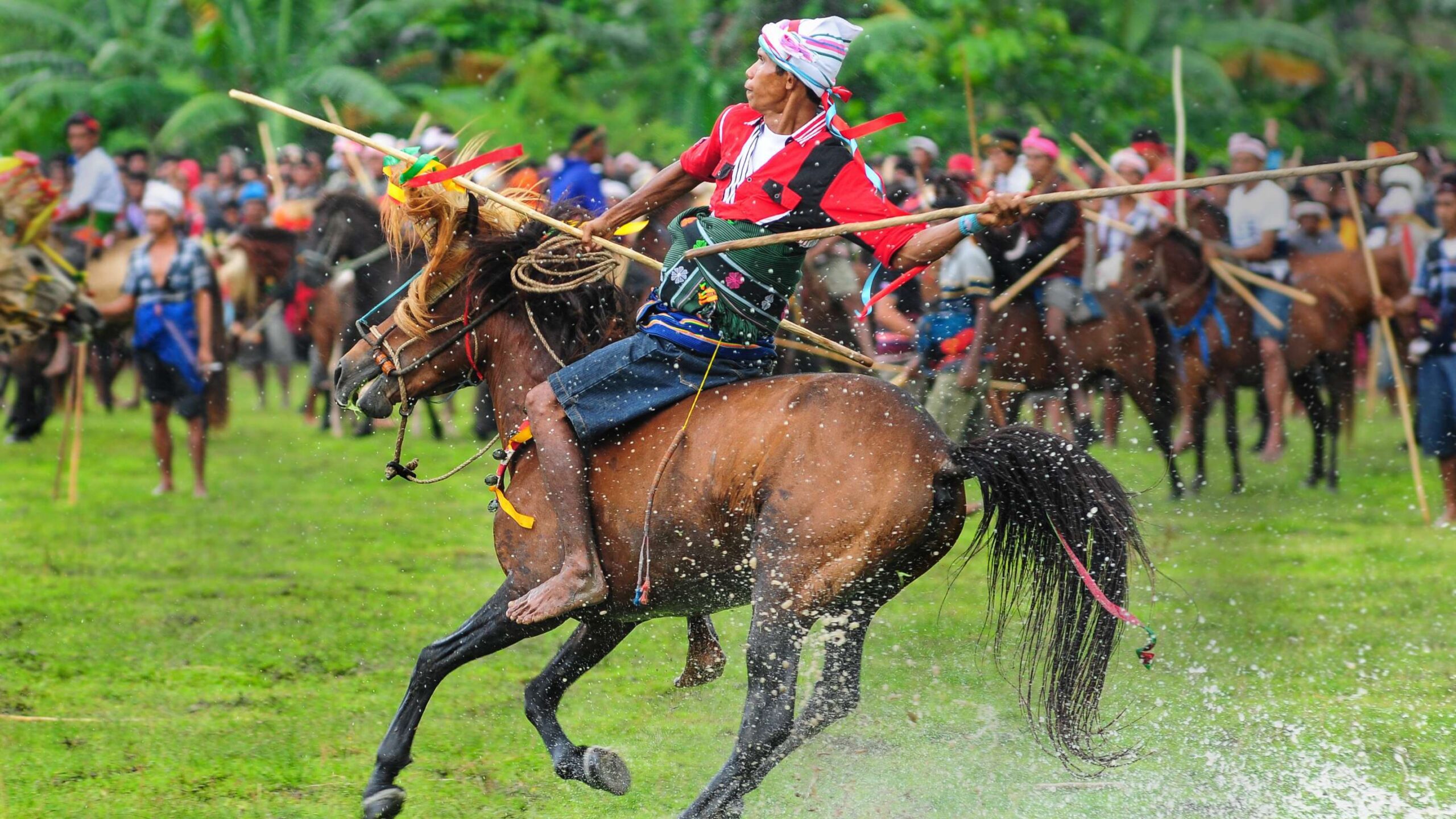 Cavaliers au galop pendant le Pasola près du village de Ratenggaro à Sumba