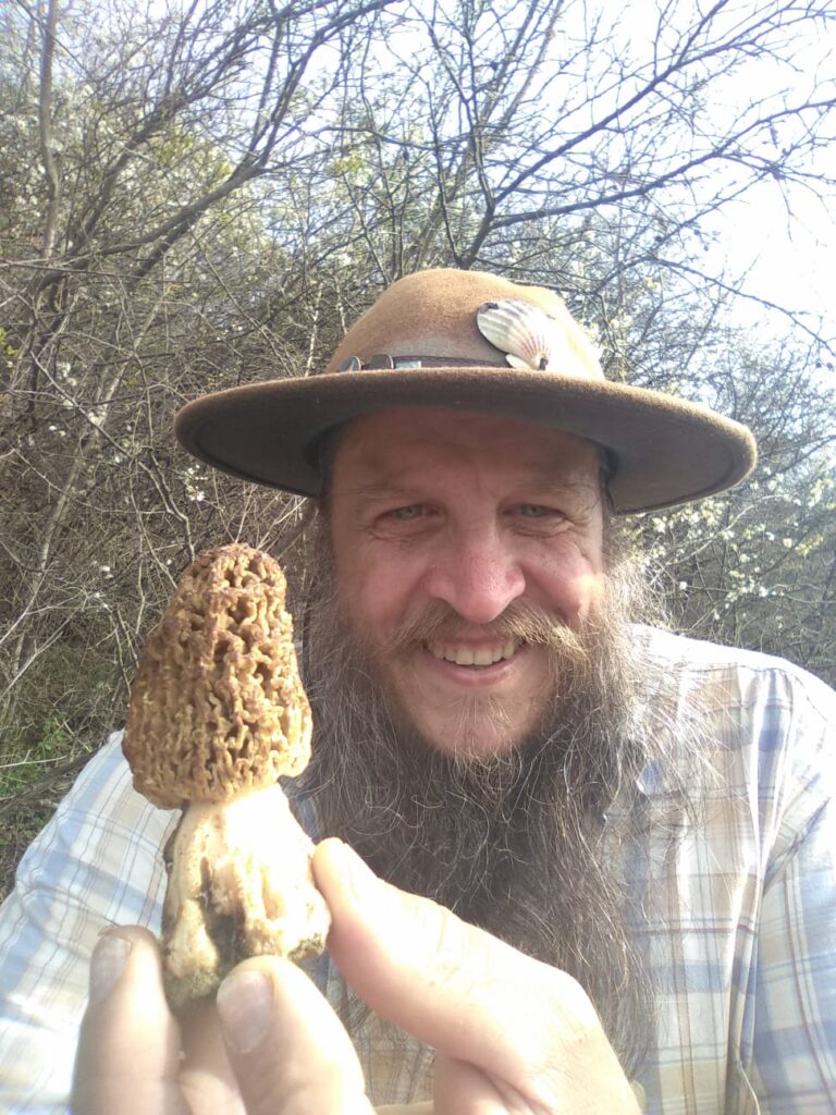 Emmanuel marcheur pèlerin tenant un champignon ramassé sur le chemin